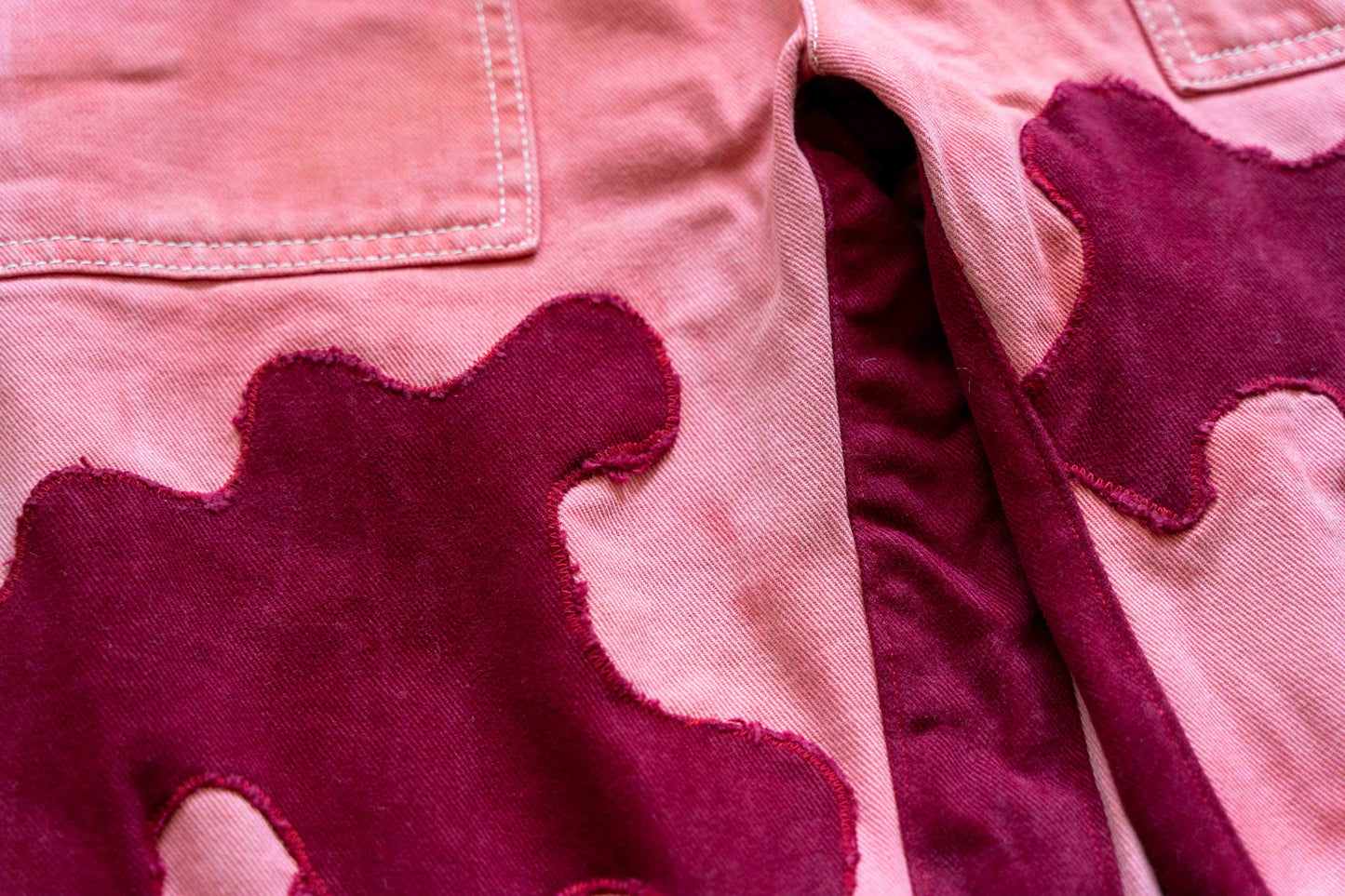 Close-up of the Rows Ambition pink and red cow spotted pants highlighting its stitching.